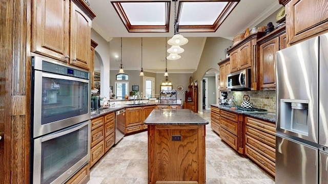 kitchen featuring kitchen peninsula, stainless steel appliances, sink, pendant lighting, and a center island