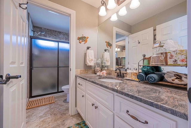 bathroom with vanity, toilet, and a shower with door