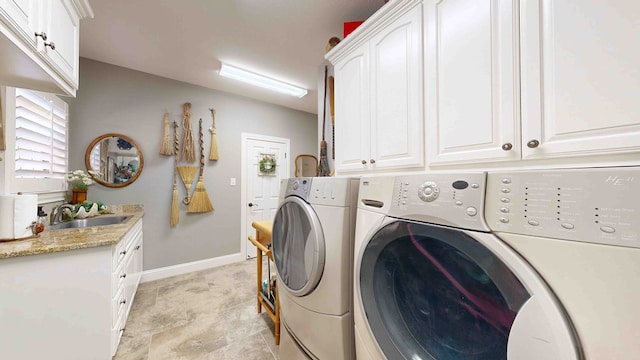 washroom with washing machine and clothes dryer, cabinets, and sink