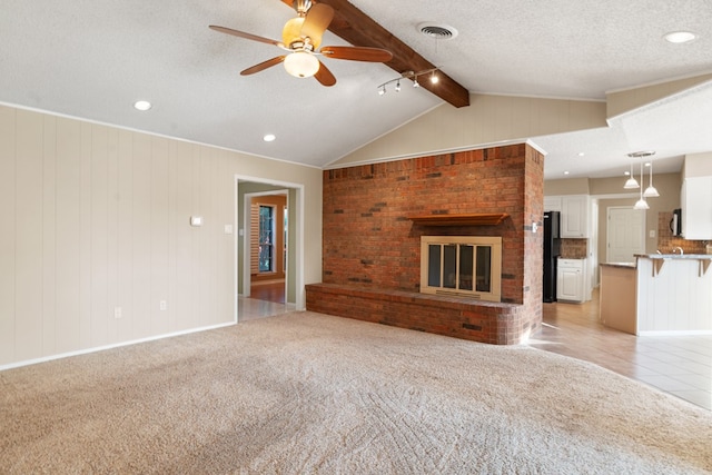 unfurnished living room featuring vaulted ceiling with beams, light colored carpet, and a textured ceiling