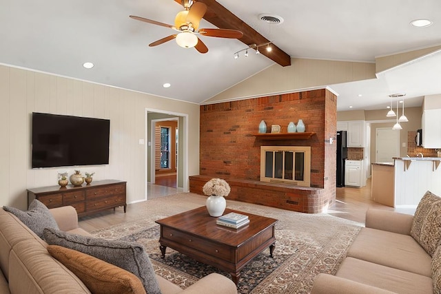 living room with vaulted ceiling with beams, ceiling fan, wood walls, and a brick fireplace