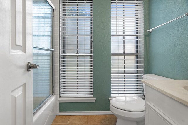 full bathroom featuring combined bath / shower with glass door, tile patterned floors, vanity, and toilet