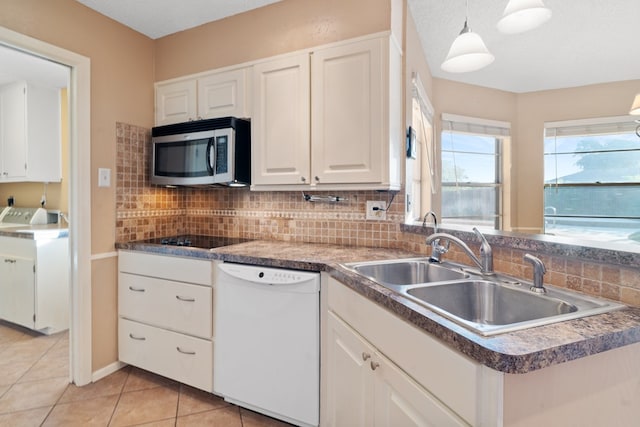 kitchen with dishwasher, white cabinets, sink, decorative light fixtures, and washer / dryer