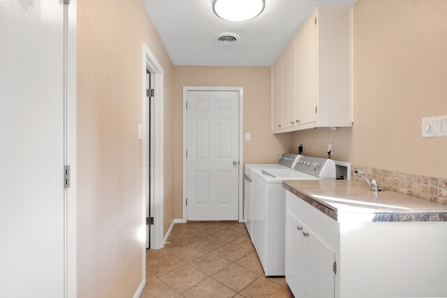 washroom with washer and dryer, light tile patterned floors, cabinets, and a textured ceiling