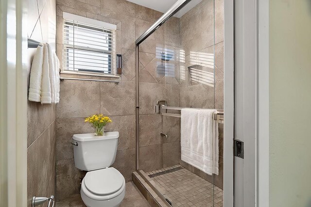 bathroom featuring tile patterned floors, toilet, and walk in shower