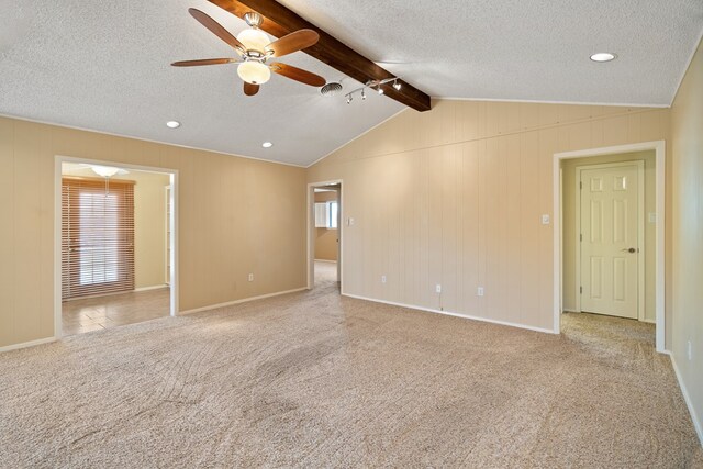 carpeted empty room featuring a textured ceiling, lofted ceiling with beams, plenty of natural light, and ceiling fan