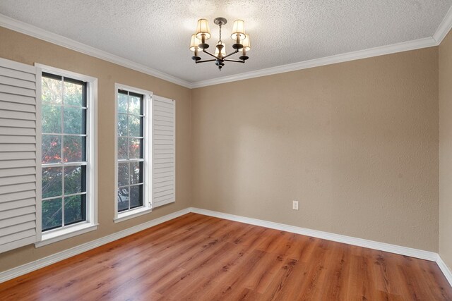 spare room featuring a textured ceiling, hardwood / wood-style flooring, an inviting chandelier, and crown molding