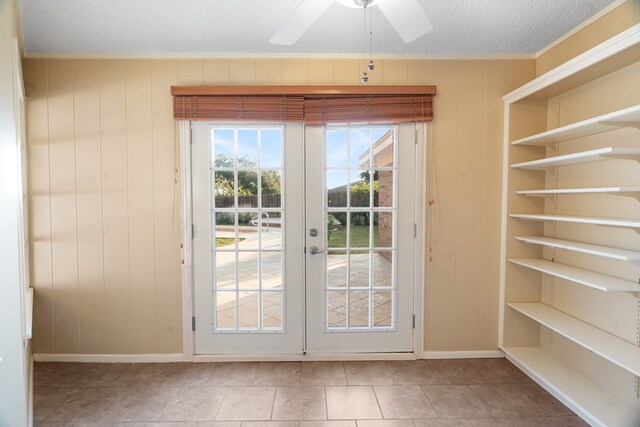 doorway to outside featuring wood walls, french doors, ceiling fan, and a textured ceiling