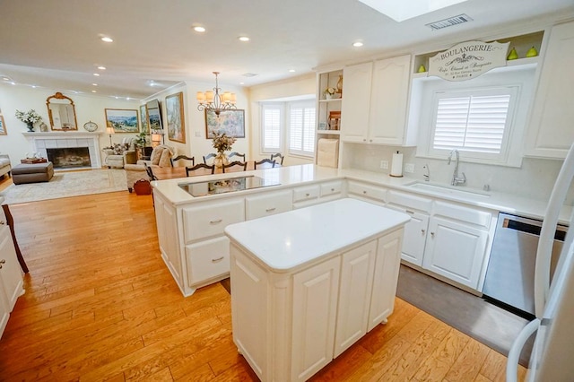 kitchen featuring sink, hanging light fixtures, light wood-type flooring, black electric cooktop, and a kitchen island