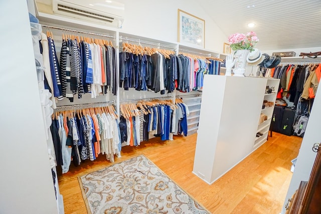 spacious closet with hardwood / wood-style floors, lofted ceiling, and a wall mounted AC