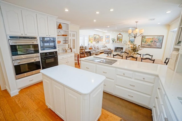 kitchen with stainless steel double oven, light hardwood / wood-style flooring, white cabinets, a center island, and hanging light fixtures