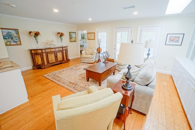 living room featuring ornamental molding, light hardwood / wood-style flooring, and a skylight