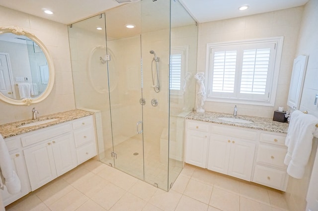 bathroom with a shower with door, vanity, and tile patterned flooring