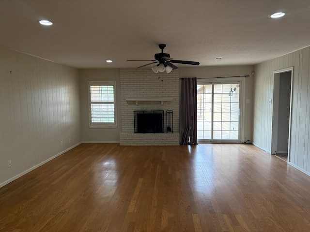 unfurnished living room featuring a ceiling fan, wood finished floors, a brick fireplace, baseboards, and recessed lighting