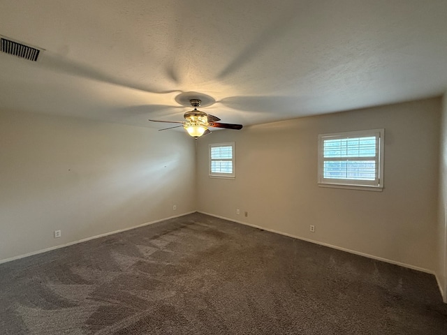 spare room with dark carpet, a ceiling fan, and baseboards