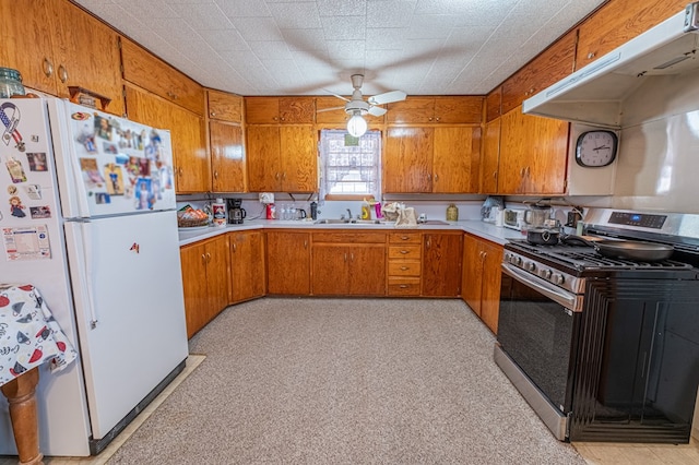 kitchen featuring ceiling fan, white refrigerator, sink, and stainless steel gas range oven