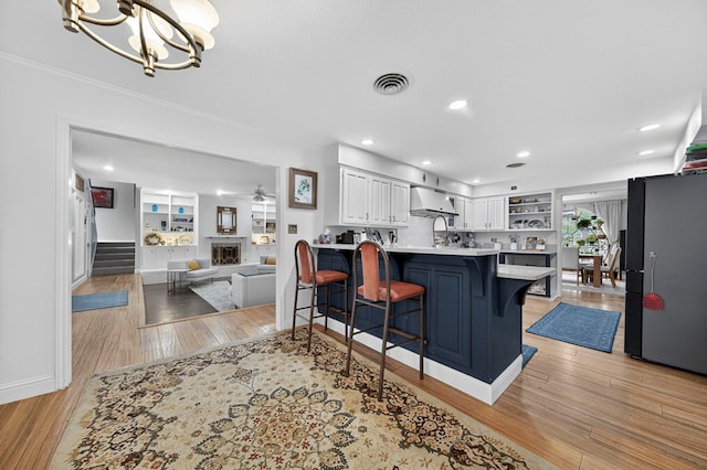 4502 Green Tree Blvd, Midland, TX 79707 - kitchen featuring freestanding refrigerator, ventilation hood, open shelves, light wood-style flooring, and recessed lighting