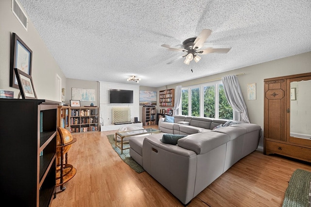 4502 Green Tree Blvd, Midland, TX 79707 - living room with a textured ceiling, wood finished floors, a ceiling fan, and a fireplace