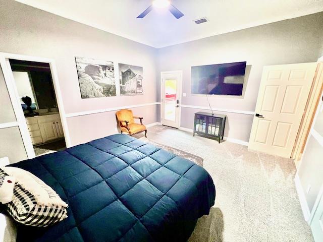 carpeted bedroom featuring a ceiling fan, baseboards, visible vents, and ensuite bath