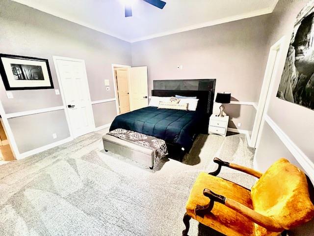 carpeted bedroom with crown molding, baseboards, and ceiling fan