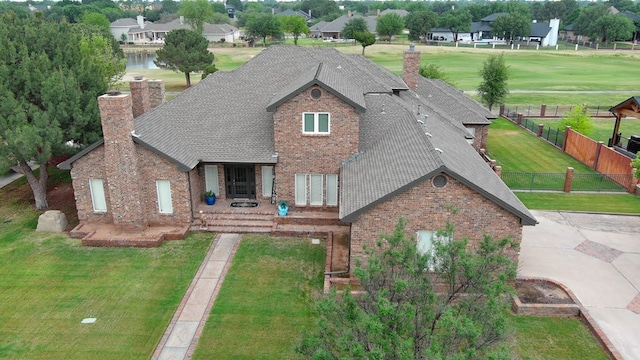 view of front facade featuring brick siding, fence, a front yard, and a chimney