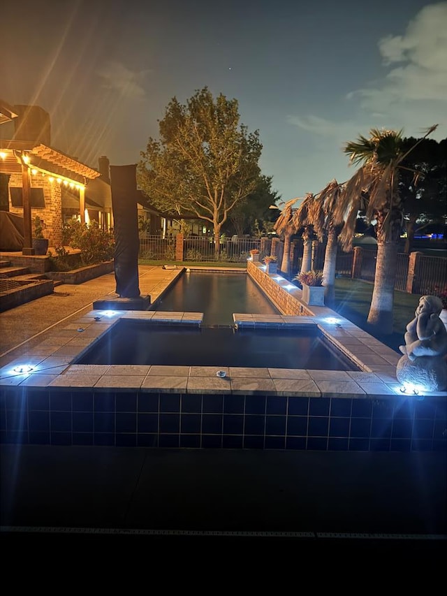 pool at twilight with fence, an in ground hot tub, and a fenced in pool