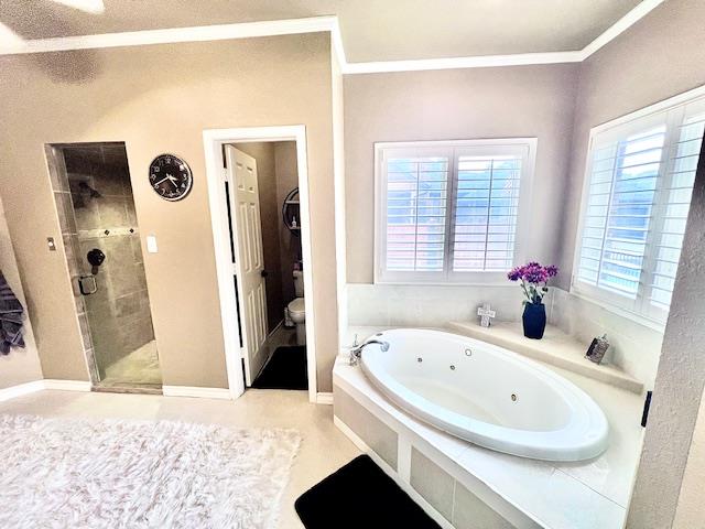 bathroom with a jetted tub, ornamental molding, a stall shower, and toilet