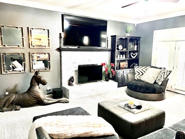 living area with ceiling fan, ornamental molding, carpet, and a fireplace