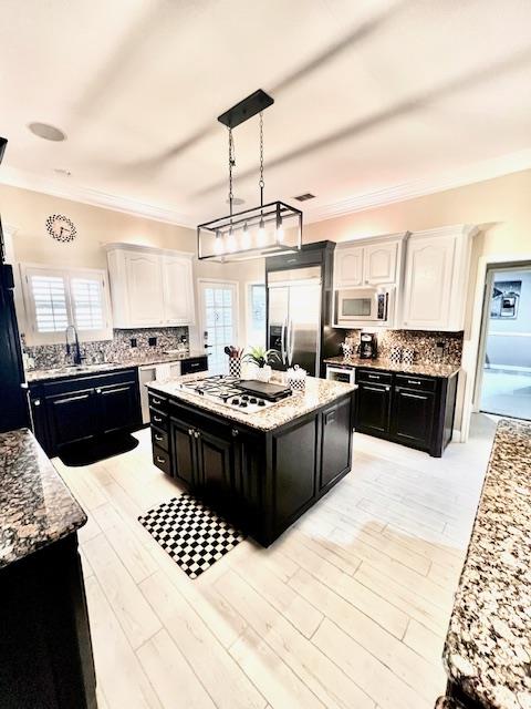 kitchen featuring dark cabinets, built in appliances, backsplash, and light stone counters