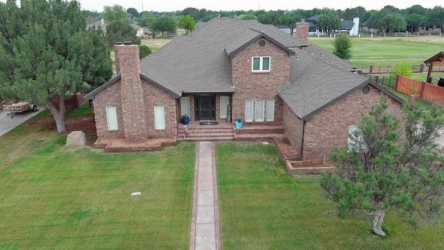 traditional-style home featuring brick siding, a shingled roof, and a chimney