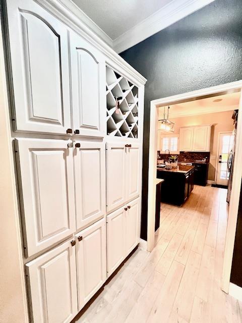 hall featuring light wood-style floors and ornamental molding