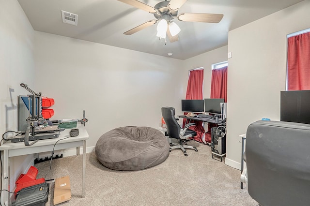 home office with a ceiling fan, visible vents, light carpet, and baseboards