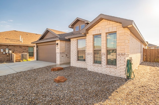 view of front of property featuring driveway, an attached garage, fence, central AC, and brick siding