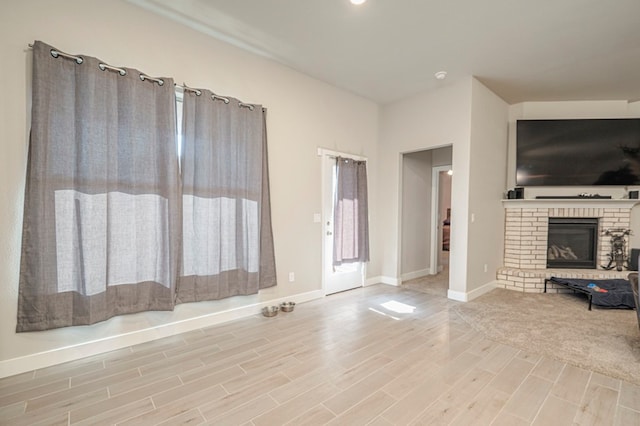 unfurnished living room with light wood-type flooring, a fireplace, and baseboards