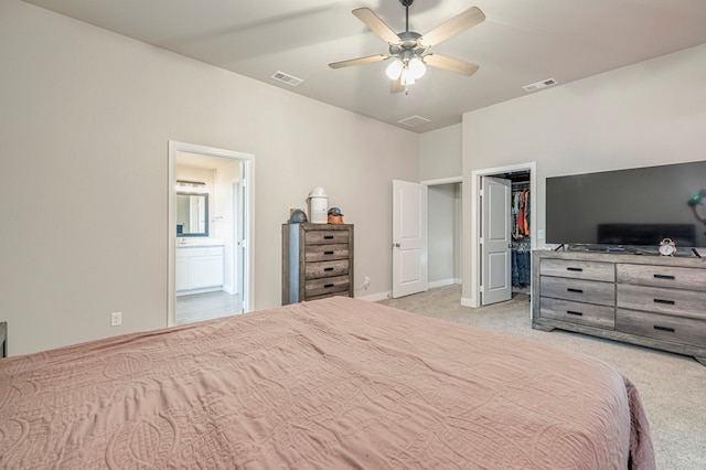 bedroom with connected bathroom, a walk in closet, visible vents, and light colored carpet