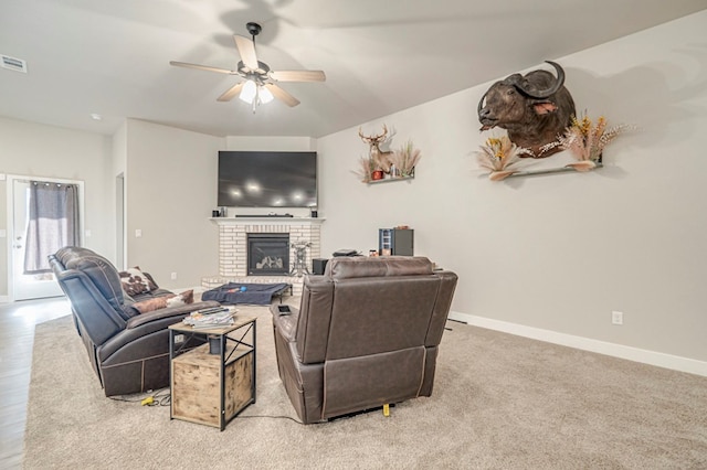 living area featuring ceiling fan, a fireplace, light colored carpet, and baseboards