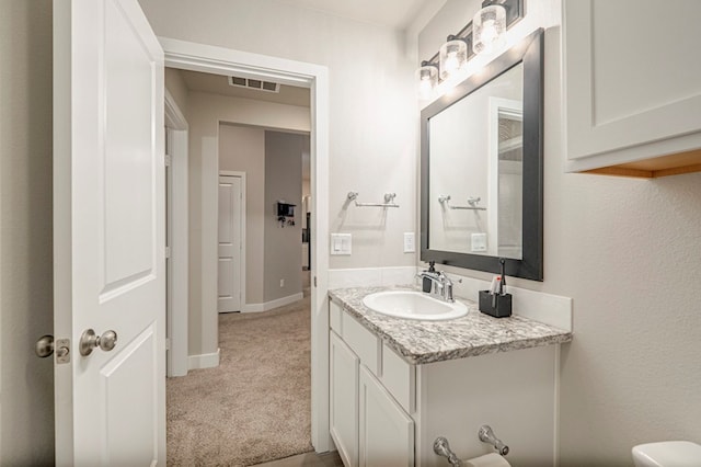 half bathroom with visible vents, vanity, and baseboards