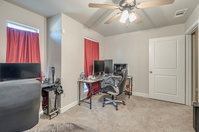 office space with baseboards, visible vents, a ceiling fan, and light colored carpet