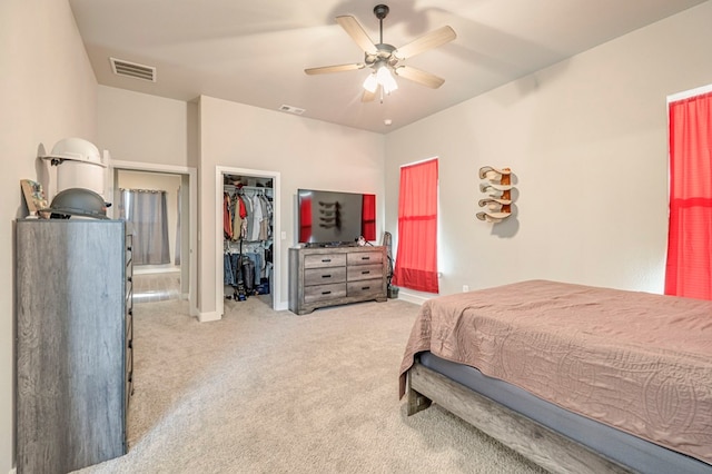 bedroom with light carpet, ceiling fan, a walk in closet, and visible vents