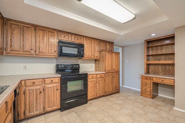 kitchen featuring a tray ceiling, built in desk, and black appliances