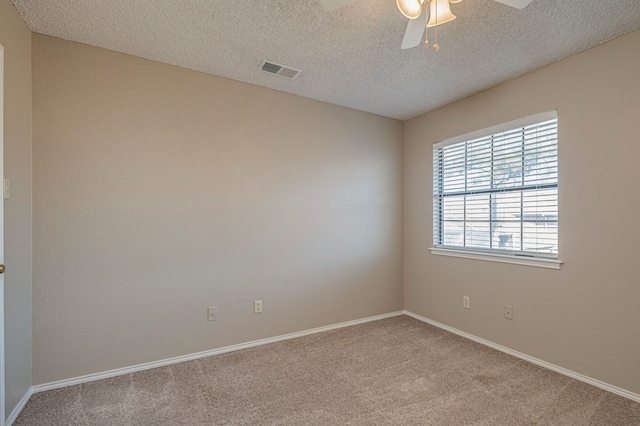 spare room with ceiling fan, light carpet, and a textured ceiling