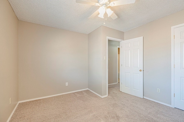 empty room with ceiling fan, light carpet, and a textured ceiling