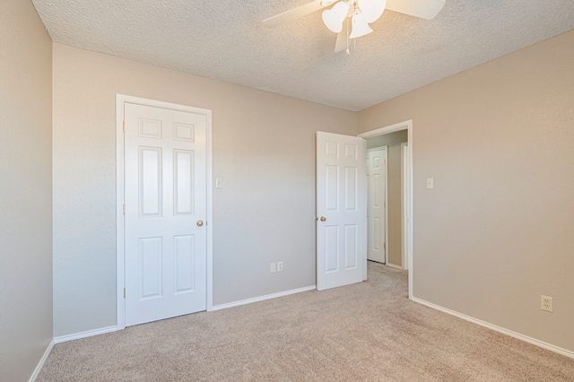 unfurnished bedroom with ceiling fan, light colored carpet, and a textured ceiling