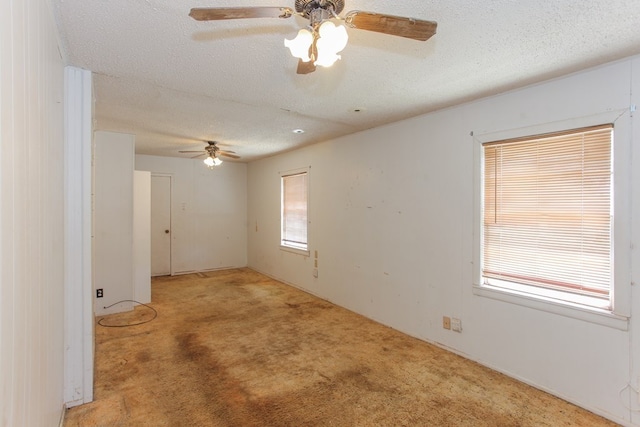 carpeted empty room featuring ceiling fan, a textured ceiling, and a wealth of natural light