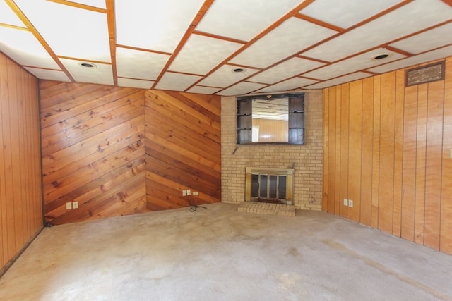 unfurnished living room featuring wood walls, carpet, and a brick fireplace