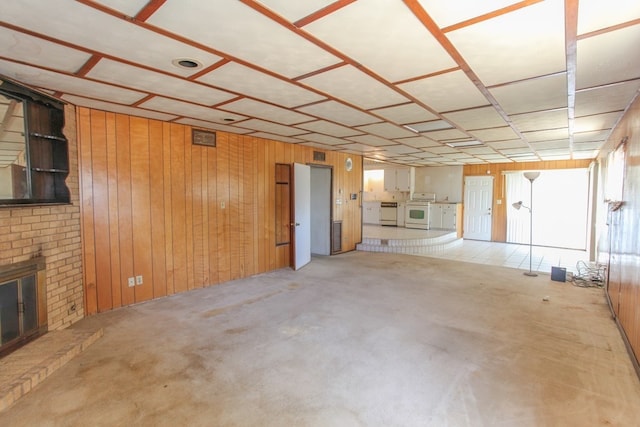 unfurnished living room featuring wood walls, independent washer and dryer, and a brick fireplace