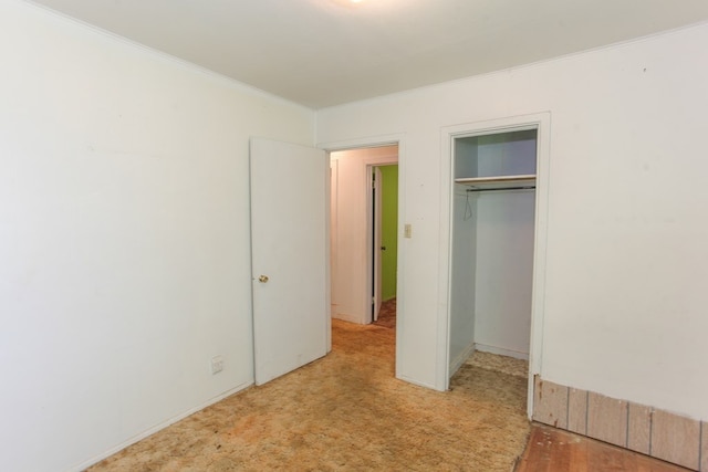 unfurnished bedroom with light colored carpet, a closet, and ornamental molding