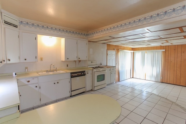 kitchen featuring wooden walls, sink, white cabinets, and white appliances