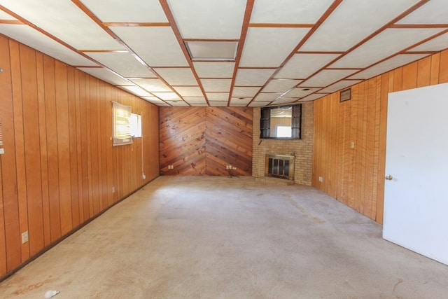 unfurnished living room featuring wood walls, a healthy amount of sunlight, light colored carpet, and a brick fireplace