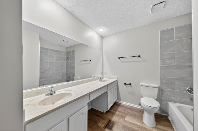3208 Preston Dr, Midland, TX 79707 - bathroom featuring double vanity, a textured ceiling, wood finished floors, and washtub / shower combination